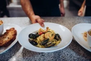 Le chef apporte une assiette de pâtes, Pappardelle au curry de Madras & Gambas