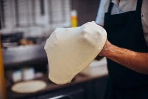 préparation de pâte à pizza dans les mains du pizzaiolo