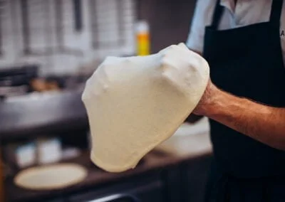 préparation de pâte à pizza dans les mains du pizzaiolo