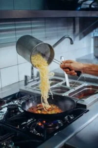 Pâtes versées dans la poêlée de légumes frais