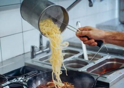 Pâtes versées dans la poêlée de légumes frais