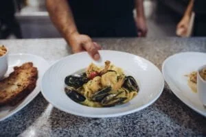 Le chef apporte une assiette de pâtes, Pappardelle au curry de Madras & Gambas
