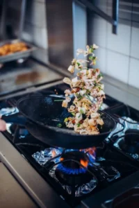 ingredients sautant dans une poele sur le piano à anglet